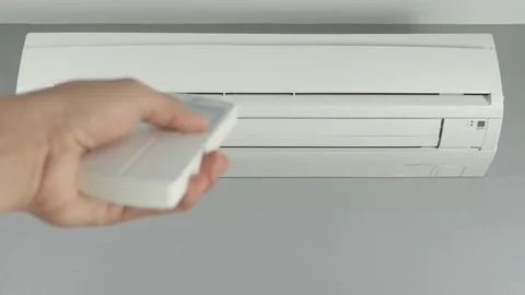 Hand holding remote control and turning on air conditioner at home Stock Footage 73900942