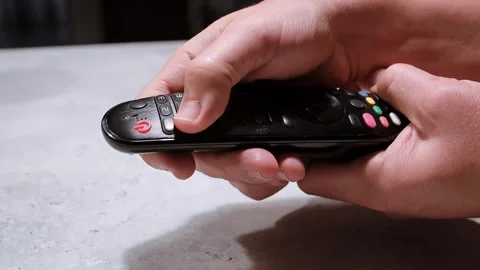 Hand Holding a Remote Control and entering the password. Press the button to Stock Footage 323766094