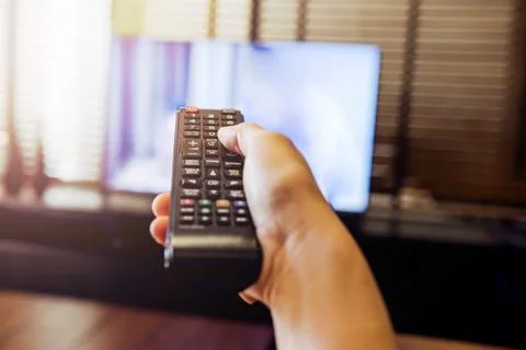 Hand Holding Remote Control and Watching TV Stock Photos