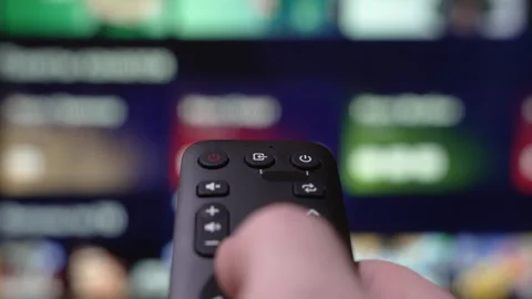 Hand Holding a Remote Control Browses Various Streaming Services On a Large Stock Footage 310602183
