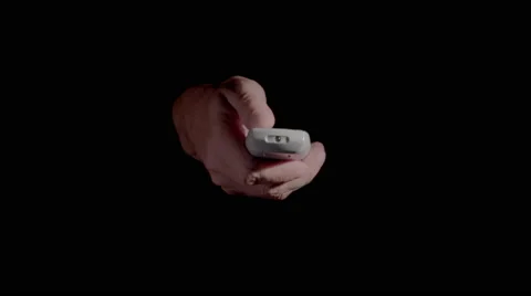 Hand Holding Remote Control Emerging From Black Background 4K Stock Footage