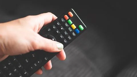 A hand holding remote control fingers black buttons tv Stock Photos