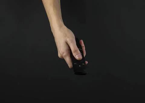 Hand holding remote control over black background Stock Photos