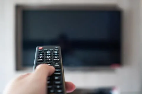 Hand holding remote control point to television Stock Photos