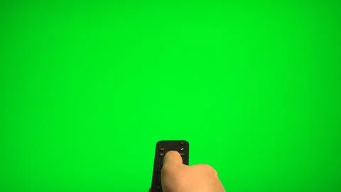 Hand holding remote control pointing at green screen TV mockup. Stock Photos