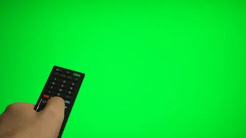 Hand holding remote control pointing at green screen TV mockup. Stock Photos