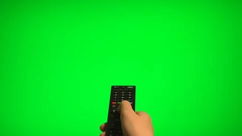 Hand holding remote control pointing at green screen TV mockup. Stock Photos