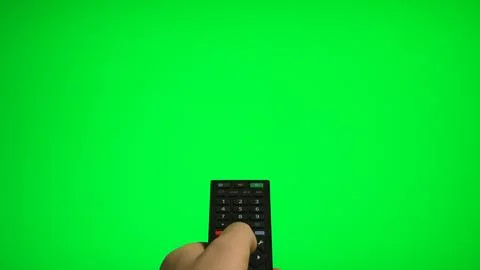 Hand holding remote control pointing at green screen TV mockup. Stock Photos