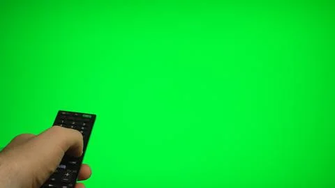 Hand holding remote control pointing at green screen TV mockup. Stock Photos