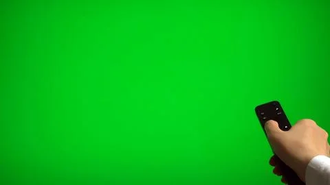 Hand holding remote control pointing at green screen TV mockup. Stock Photos