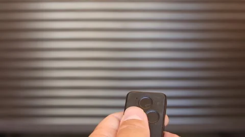 Hand holding a remote control, pressing a button to open an automatic garage Stock Footage 342768212