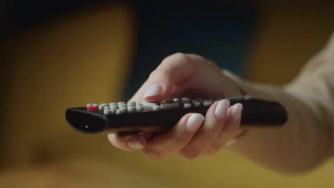 Hand holding a remote control ready to play a show in a cozy living room setting Stock-Footage 303768745