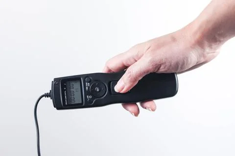 Hand holding remote control shutter switch of DSLR mirrorless camera on white Stock Photos