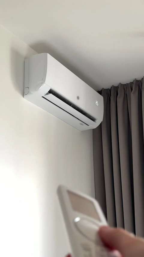 Hand holding remote control to switch on wall conditioner for seasonal dome.. Stock-Footage 346155850