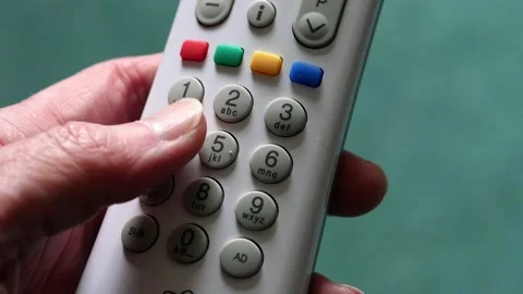 Hand holding a remote control with thumb pressing channels buttons. Stock Footage 133596937