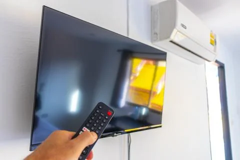 Hand Holding Remote Control Turning On Television In Thai Hotel Room Thailand Stock-Fotos