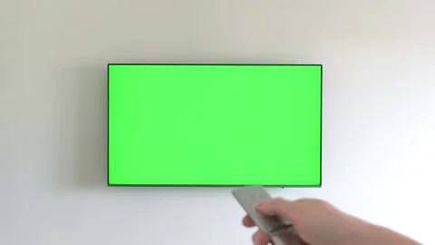 Hand holding a remote control turns on a wall mounted television displaying.. Stock Footage 338398459