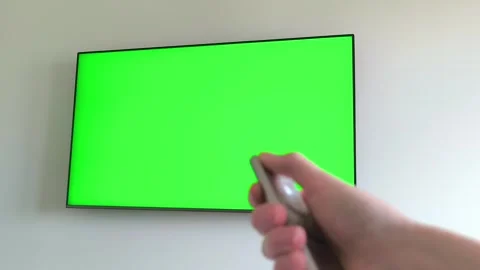 Hand holding a remote control turns off a television showing a green chroma.. Stock Footage 338398471