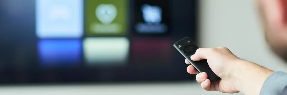 Hand Holding Remote Control While Using Smart TV Foto stock
