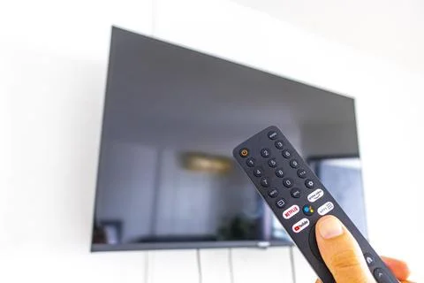 Hand holding a remote control while turning on a television Thailand. Stock Photos