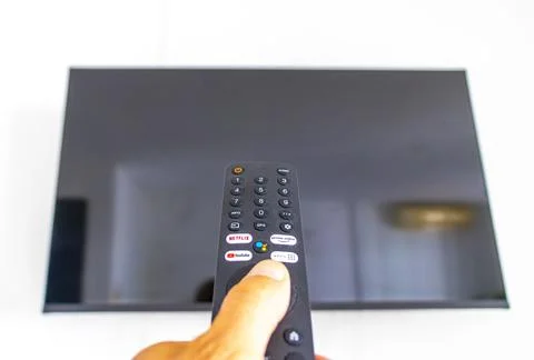 Hand holding a remote control while turning on a television Thailand. Stock Photos