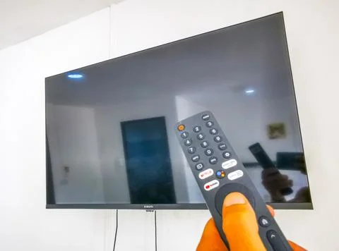 Hand holding a remote control while turning on a television Thailand. Stock Photos