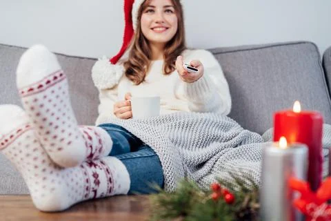 Hand holding remote controller with blurred smiling woman in santa hat, warm Stock Photos