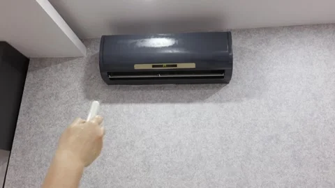 Hand holding remote controlling air conditioner, climate control Video stock 329237899