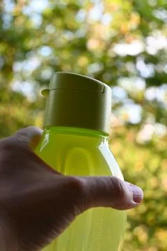 Hand holding a reusable drinking bottle outdoors Stock-Fotos