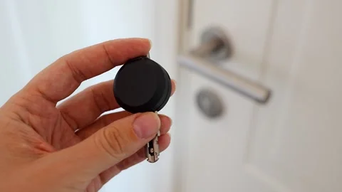 Hand holding an RFID key fob in front of an apartment door with lock and handle Stock Footage 345652999