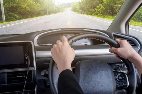 Hand holding right steering wheel with highway in rural Stock Photos