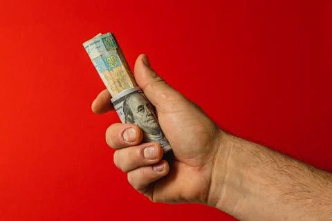 Hand holding rolled bank notes against red backdrop Stock Photos