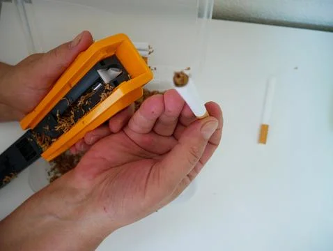 Hand Holding Rolling Machine with Finished Hand-Rolled Cigarettes, DIY Smoking Фото