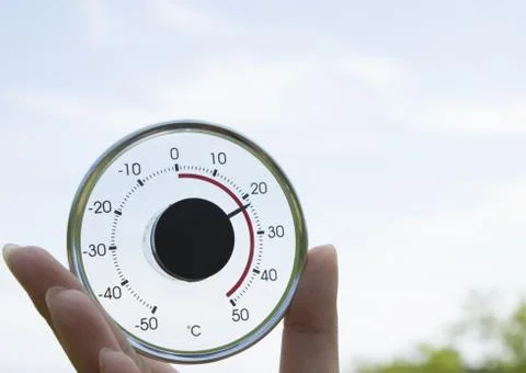 Hand holding a round thermometer Foto stock