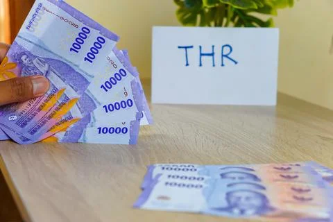 Hand holding a rupiah note with a denomination of ten thousand for THR Stock Photos