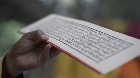 Hand holding a Sadhana text. Reciting buddhist prayers. Video stock 229848754
