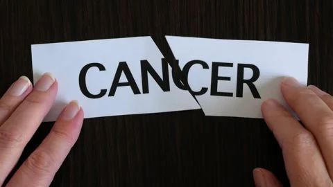 Hand holding the scissors cutting paper pieces with text CANCER on black wo.. Stock Footage 253706650