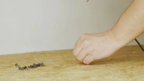 Hand holding a screw while screwing into a oriented strand board with a drill. Stock Footage 200962827