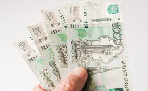 Hand holding several one thousand Russian Ruble banknotes fanned out on a whi Stock Photos