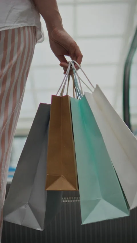 Hand holding shopping bags while ascending the escalator in a modern shoppin Stock Footage 331594763