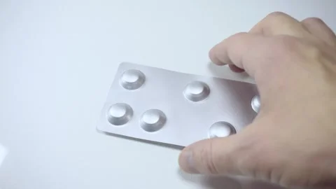 Hand holding silver blister pack with pills close up on white background Stock Footage 342838812