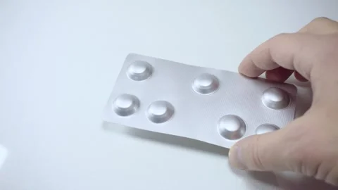 Hand holding silver blister pack with pills close up on white background Stock Footage 342838837