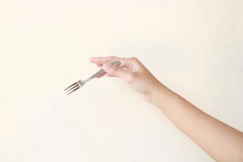 Hand Holding a Silver Fork on a Neutral Background Fotos de archivo
