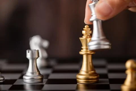 Hand holding silver king attack gold leader in game Stock Photos
