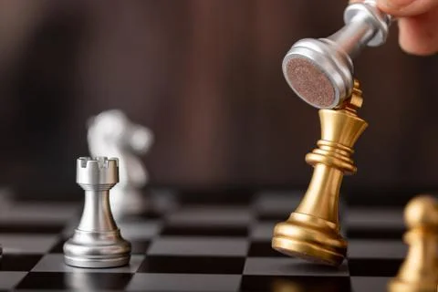 Hand holding silver king attack gold leader in game Stock Photos