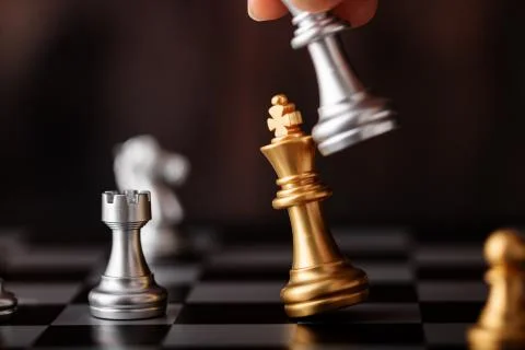 Hand holding silver king attack gold leader in game Stock Photos