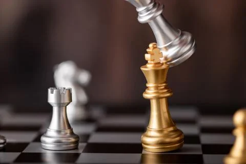 Hand holding silver king attack gold leader in game Stock Photos