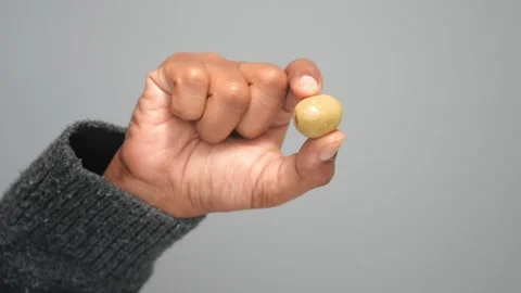 Hand holding single green olive with pit close up detail against plain back.. Stock Footage 332108835