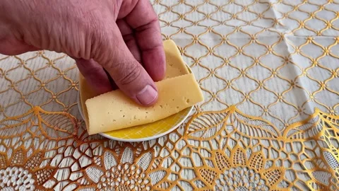 Hand Holding a Slice of Cheese on a Decorative Crochet Tablecloth Vidéo 346743587