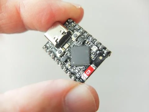 Hand holding a small black microchip microcontroller development board with t Stock Photos